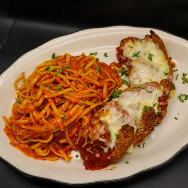 Chicken Parmesan with melted mozzarella cheese and a side of linguine pasta with red sauce.
