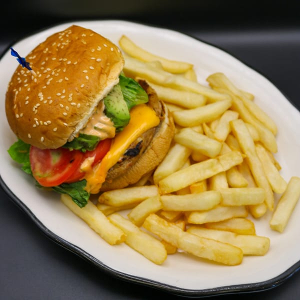 A Johnson Diner & Bar cheeseburger with lettuce, tomato, avocado, and special sauce, served with fries.